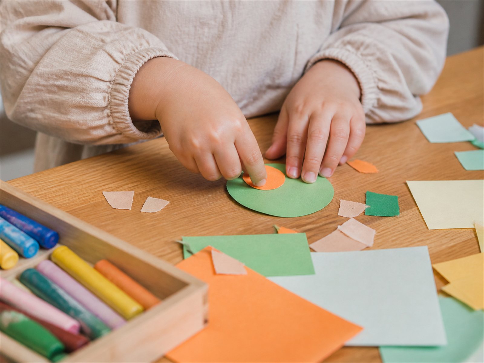 クレヨンと色画用紙で工作をする子どもの手元