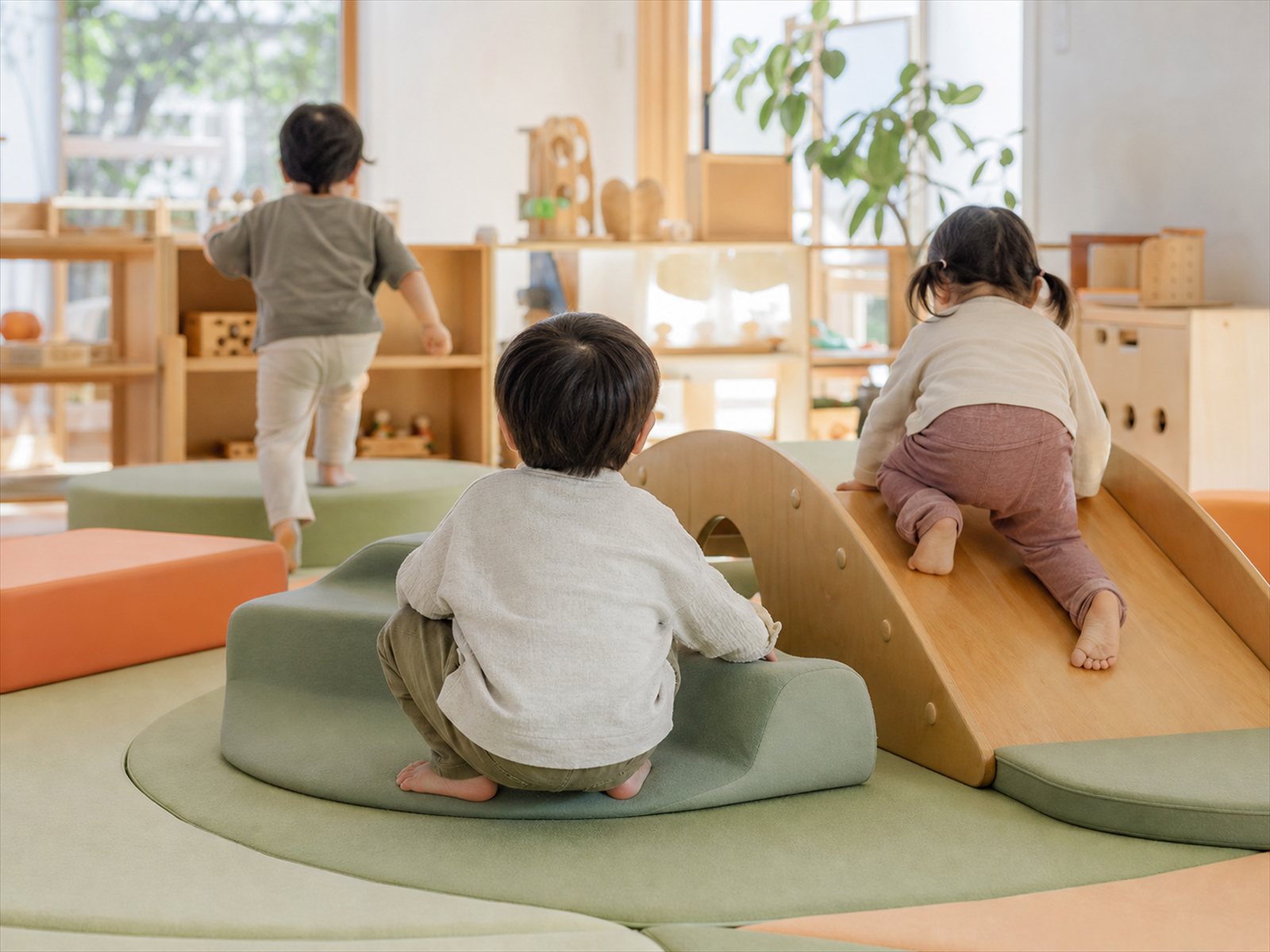 保育室のやわらかいマットの上で遊ぶ子どもたちの後ろ姿